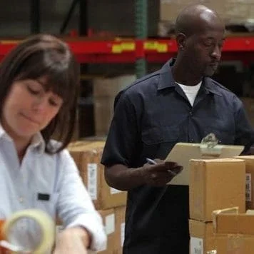 Man and a woman working in a warehouse.