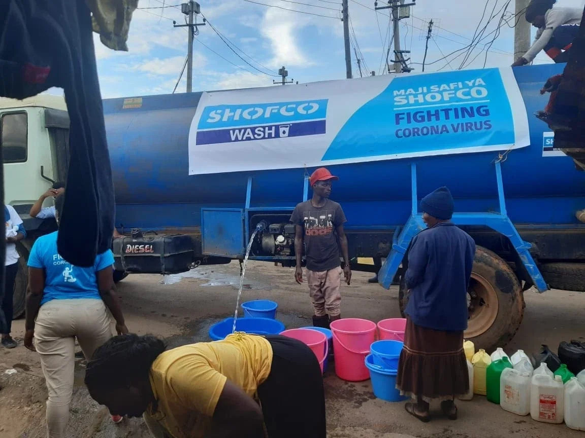 Volunteers filling buckets with water to lead hand washing in order to stop Covid-19