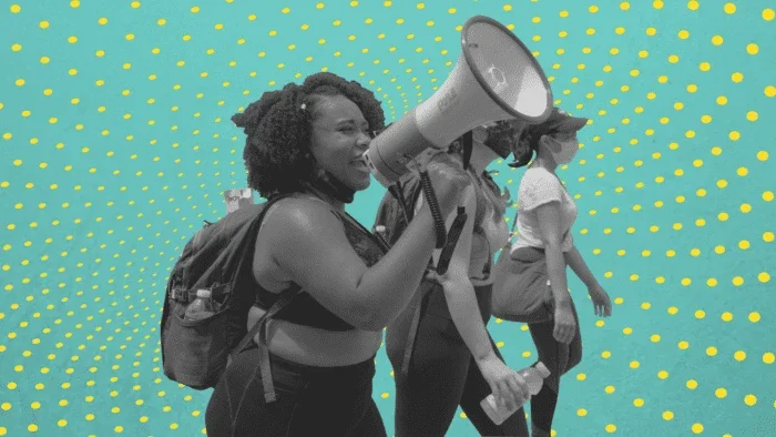 Three women protesting, with one woman speaking into a megaphone.