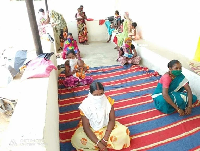 Mothers and their children wait in line in India for vaccine.