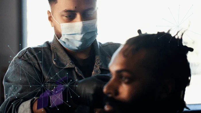 man wearing a facemask giving a man sitting a haircut