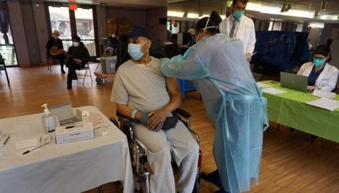 health worker giving a man receiving a vaccine shot in the arm.