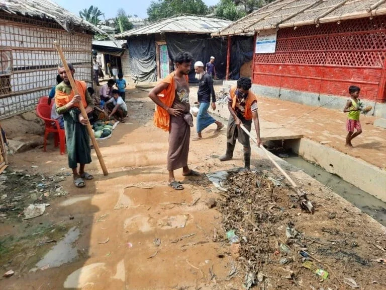 people cleaning open sewage drain