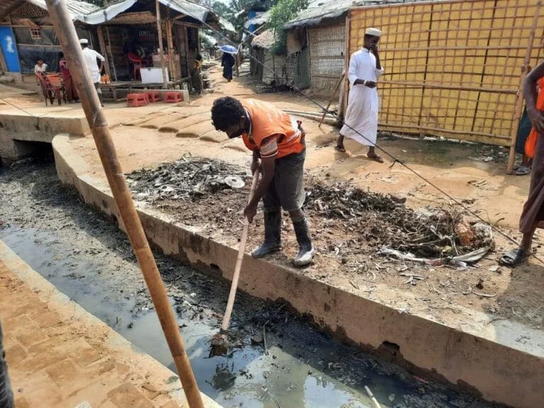 person cleaning open wastewater drains.