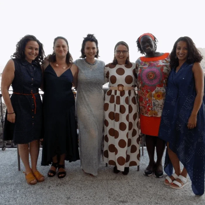 group shot of women standing with their arms around one another smiling.