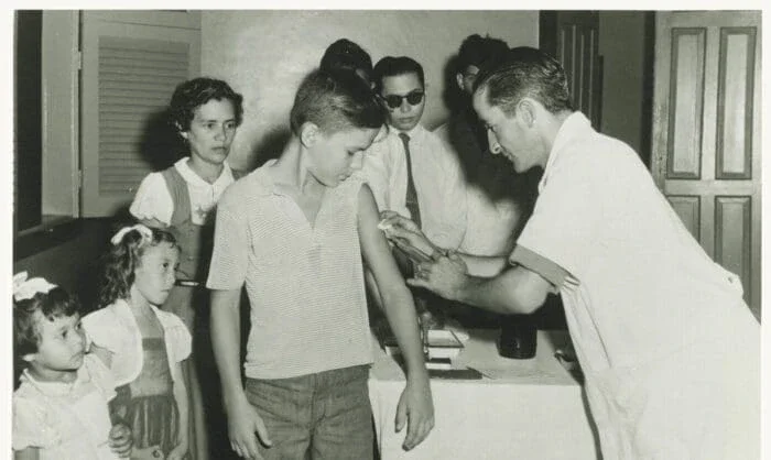 man giving a young boy a shot in the arm