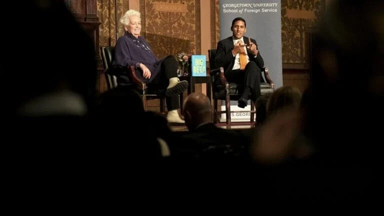 man and a woman sitting in chairs on stage talking about the new book 