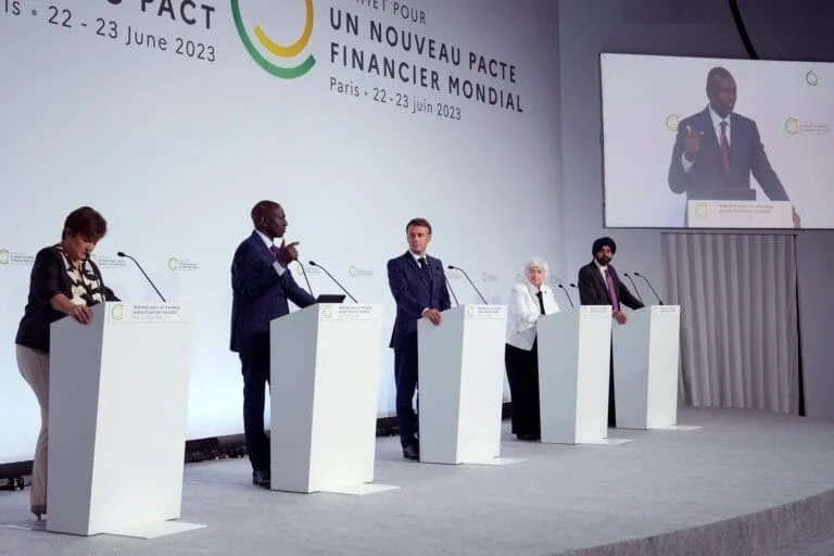 five individuals stand behind podiums on a stage during the 